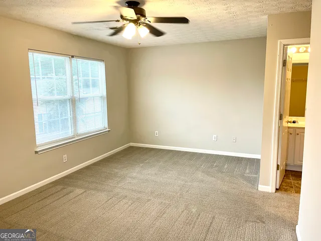 an empty room with windows and fan