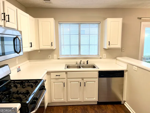 a kitchen with kitchen island granite countertop a sink stove and cabinets