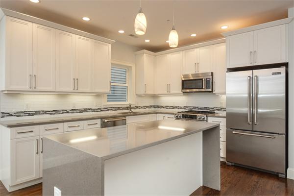 a kitchen with stainless steel appliances granite countertop a stove a refrigerator a sink and white cabinets