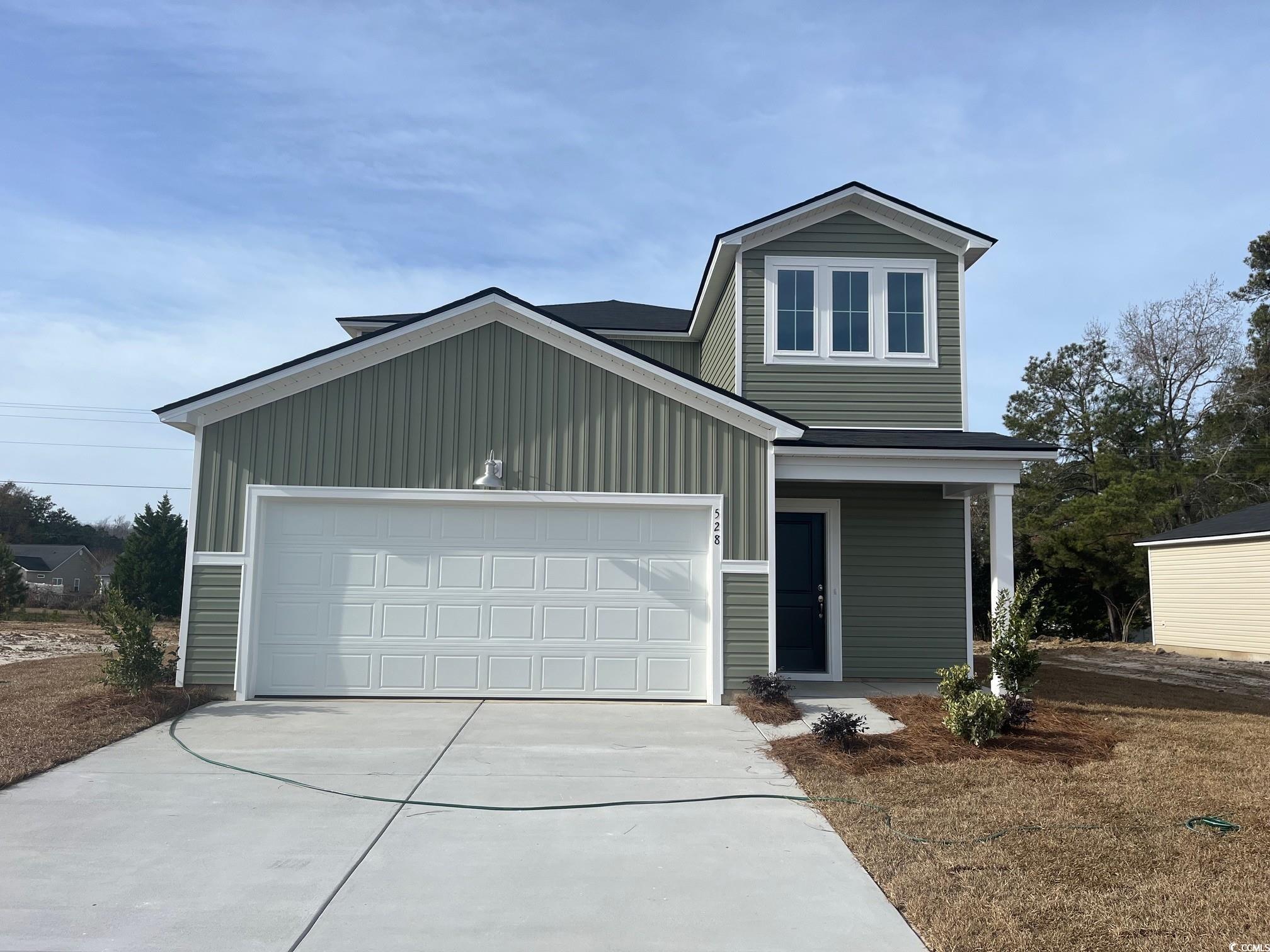 View of front of property featuring concrete driveway, a porch, a garage, and board and batten siding