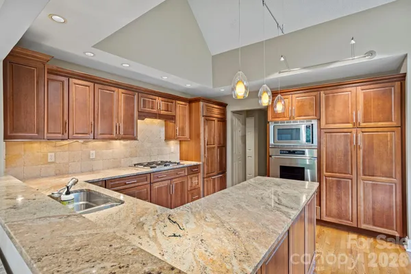 a kitchen with stainless steel appliances granite countertop a sink refrigerator and cabinets