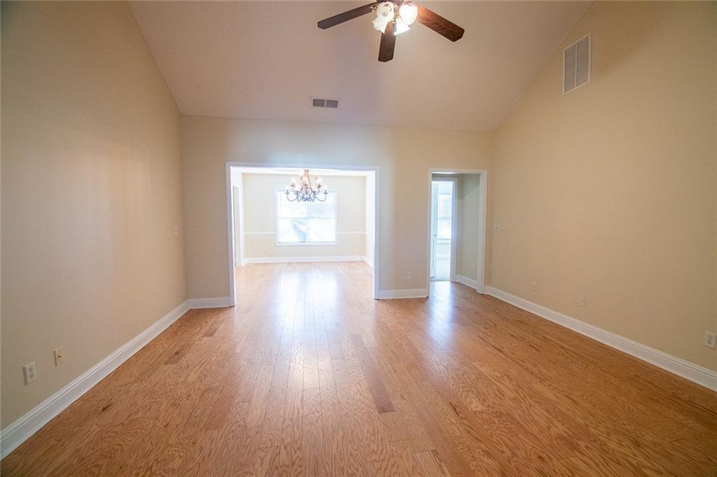 2545 Rosehill Circle Lithia Springs, GA 30122 - Photo 20 of 27 an empty room with wooden floor chandelier fan and windows