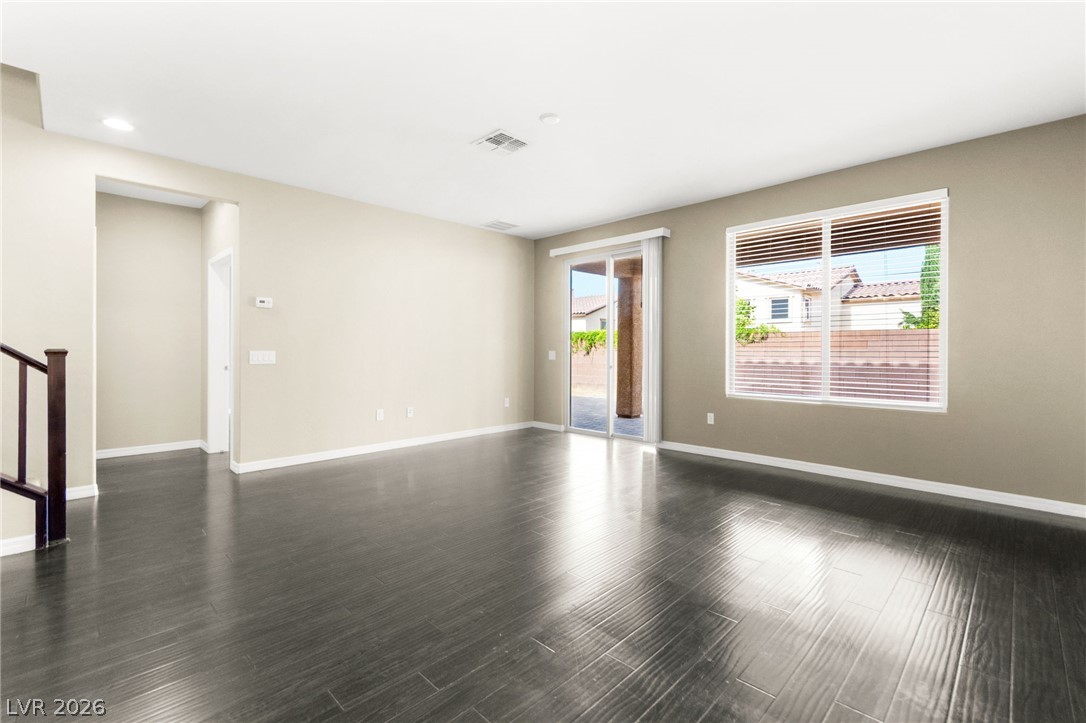 11048 Prairie Grove Road Las Vegas, NV 89179 - Photo 11 of 75 A spacious room featuring glossy dark wood flooring and a sliding glass door to outdoor living.