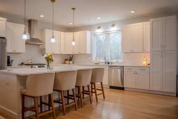 a kitchen with granite countertop white cabinets stainless steel appliances and a dining table