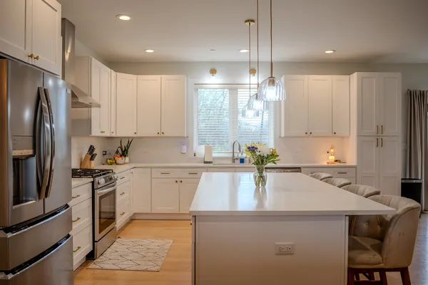 a kitchen with a sink a stove a refrigerator and white cabinets