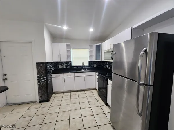 a kitchen with a refrigerator a stove top oven and cabinets