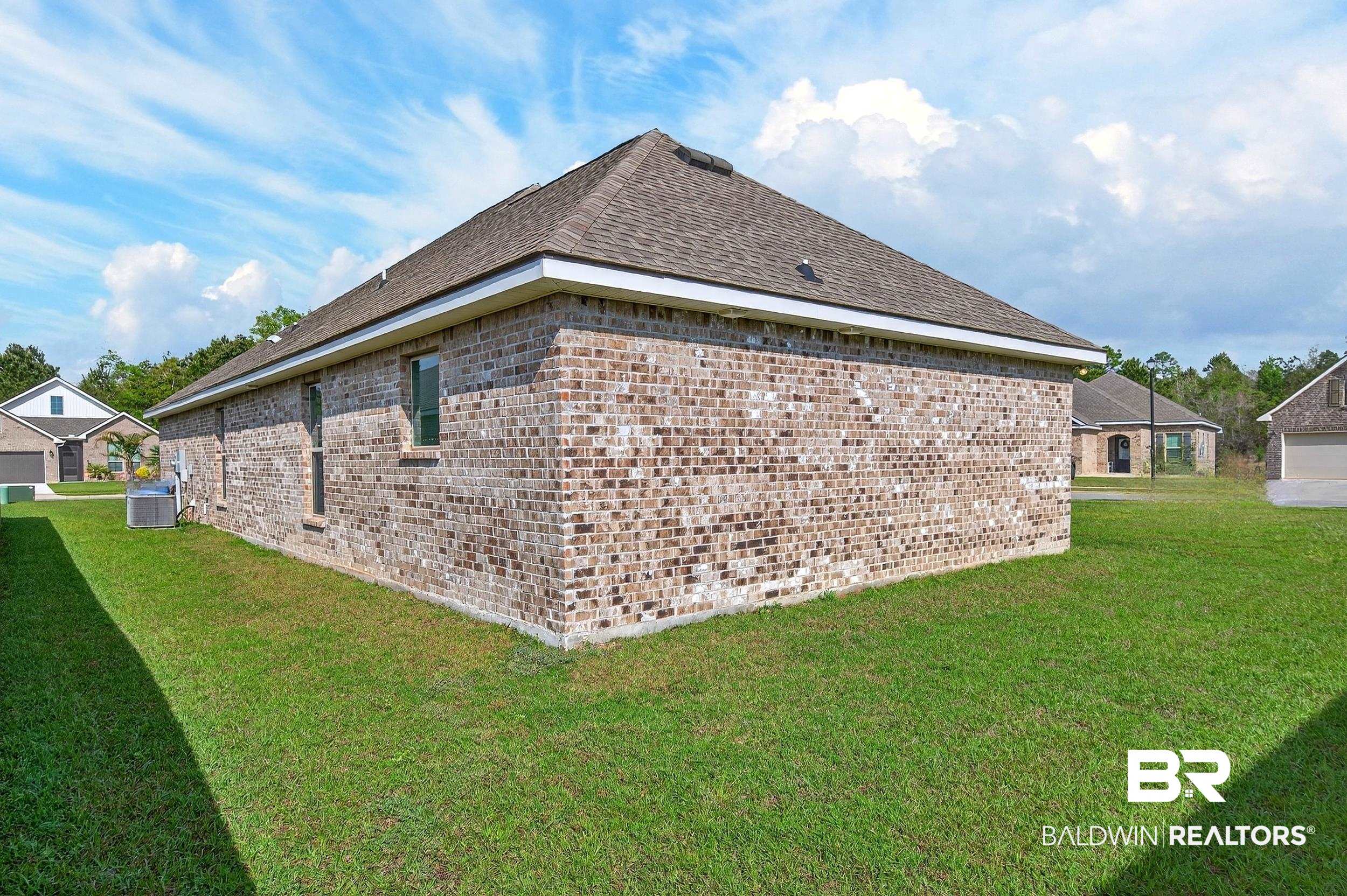 1084 Stella Road Foley, AL 36535 - Photo 30 of 31 View of side of property with brick siding, a lawn, and roof with shingles