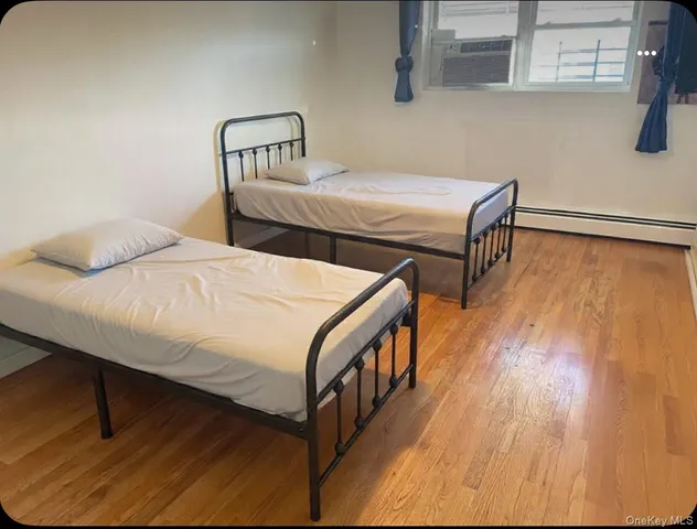 a bedroom with two beds and wooden floor