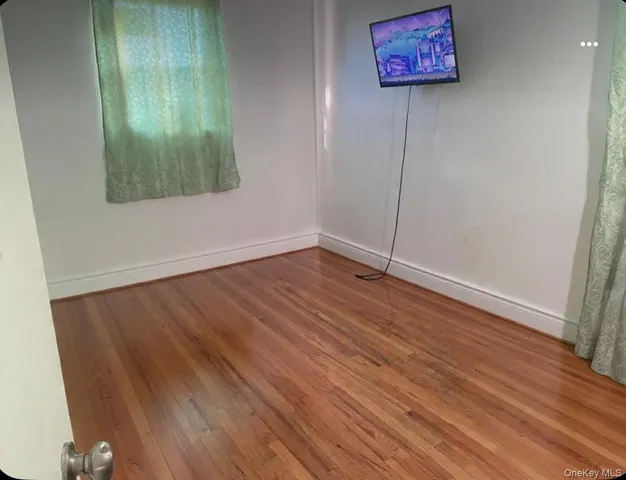 an empty room with wooden floor and a way to kitchen