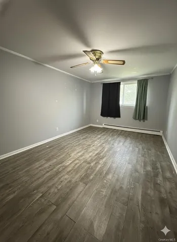 an empty room with wooden floor ceiling fan and window