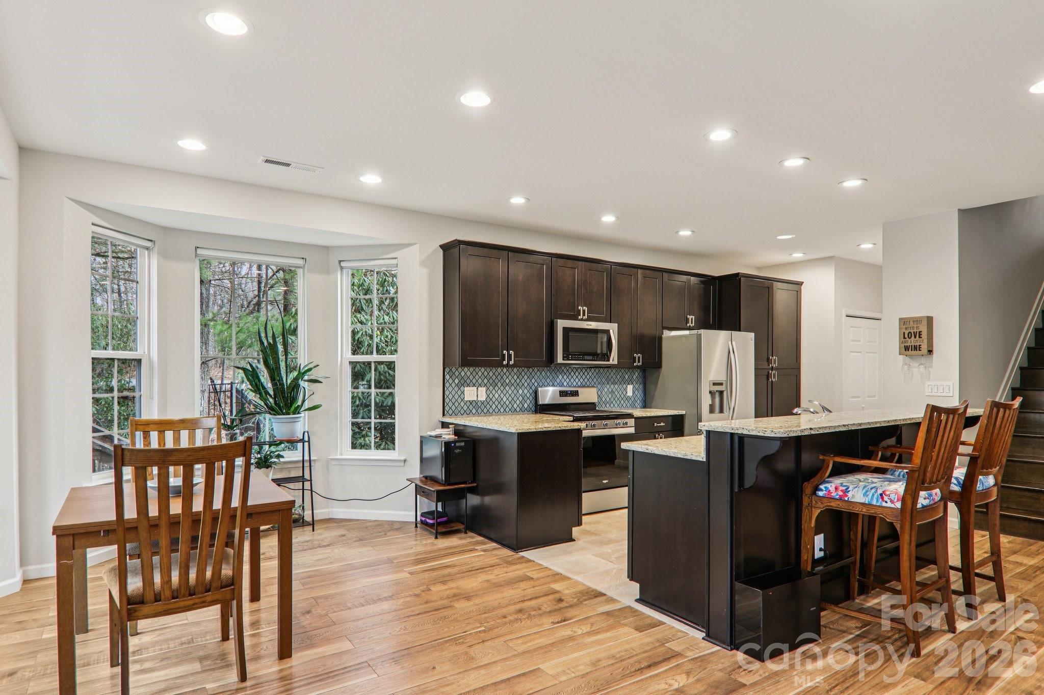 29 Saddle Top Road Flat Rock, NC 28731 - Photo 12 of 46 a kitchen with stainless steel appliances kitchen island granite countertop a table chairs a sink and a refrigerator