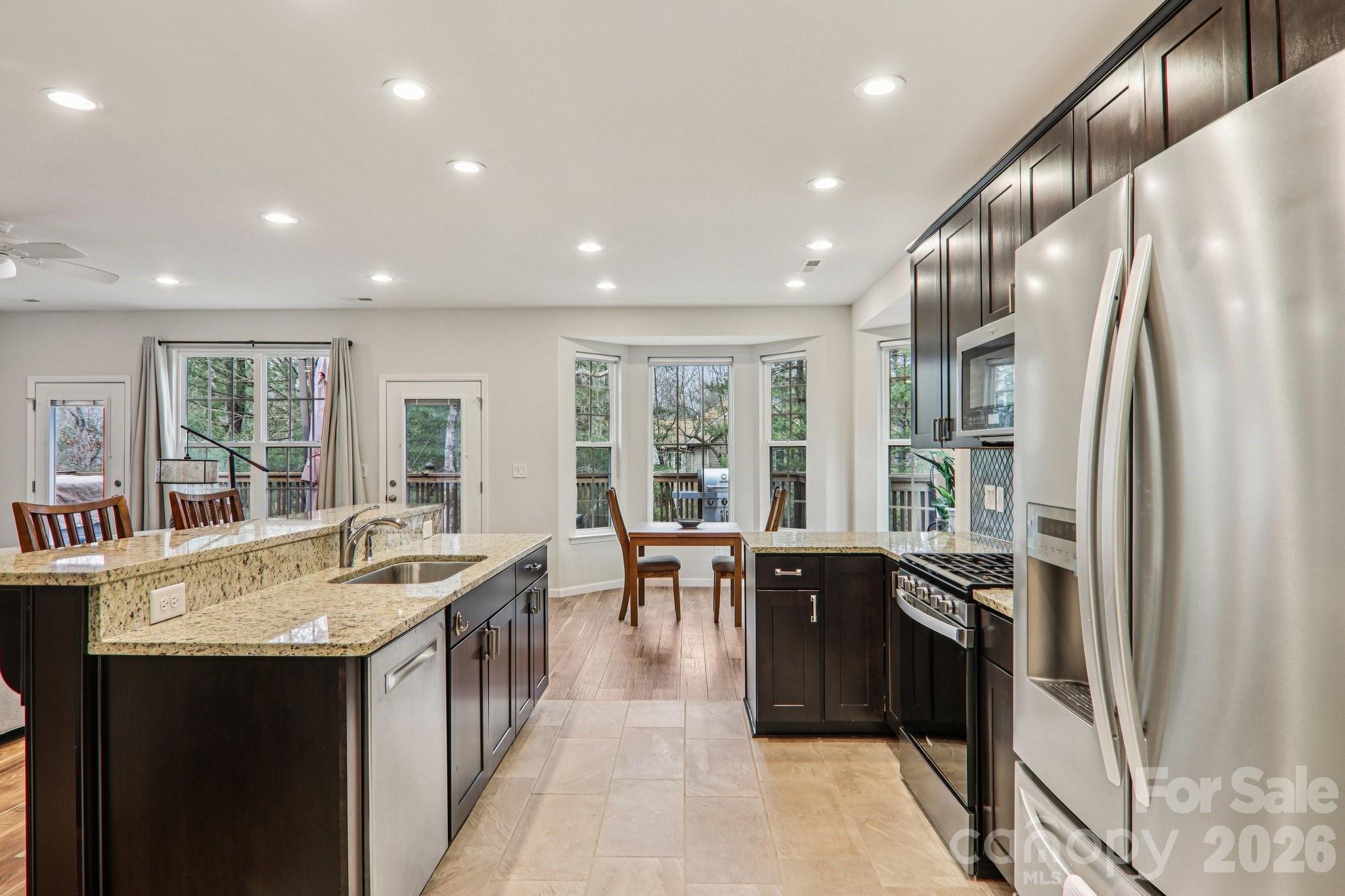 29 Saddle Top Road Flat Rock, NC 28731 - Photo 18 of 46 a kitchen with stainless steel appliances granite countertop a refrigerator a sink a stove and a dining table with wooden cabinet