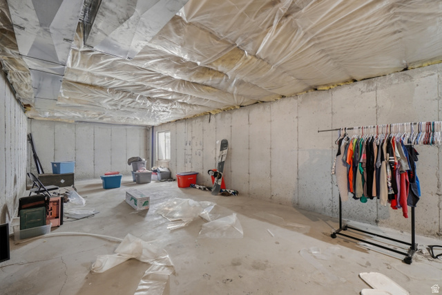 2135 East White Pine Road Eagle Mountain, UT 84005 - Photo 19 of 23 Unfinished basement featuring concrete slab flooring, exposed ceiling joists with insulation, concrete block walls, and a visible window