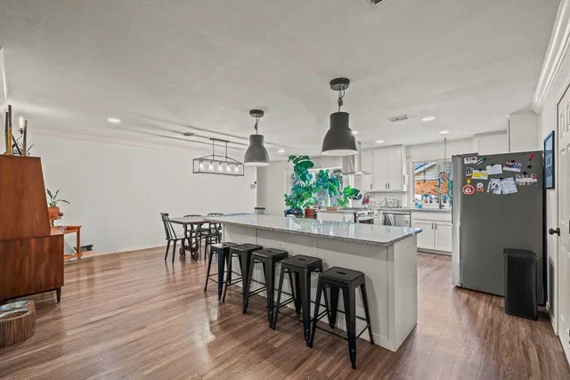 a kitchen with stainless steel appliances a dining table chairs and wooden floor