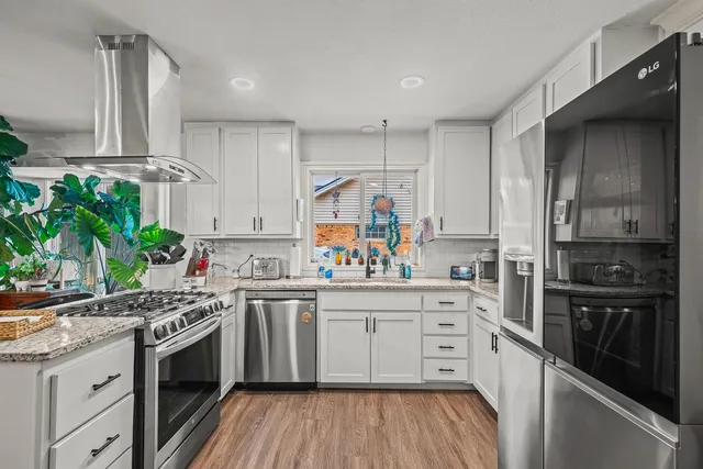 a kitchen with granite countertop cabinets stainless steel appliances and wooden floor