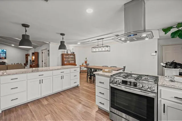 a kitchen with cabinets wooden floor and stainless steel appliances