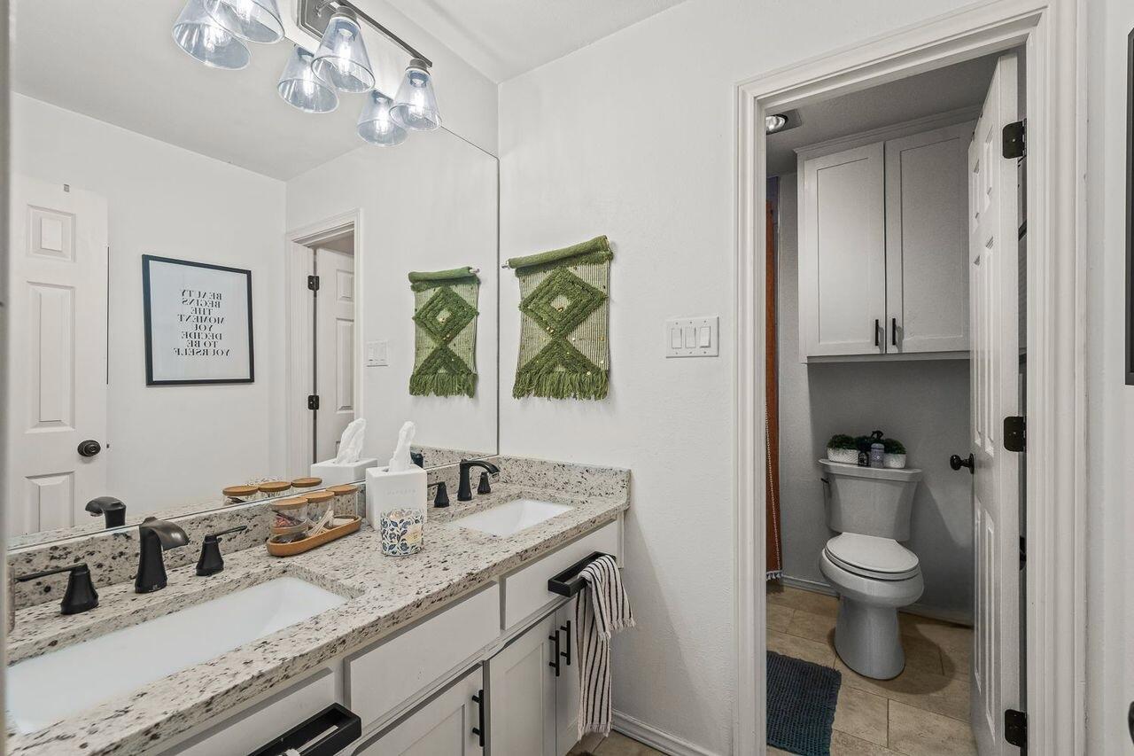 3410 94th Street Lubbock, TX 79423 - Photo 44 of 57 a bathroom with a granite countertop sink a toilet and a mirror