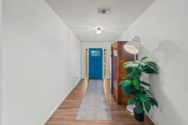 a hallway with potted plants and wooden floor