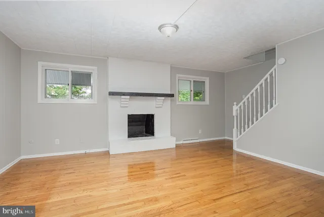 a view of empty room with wooden floor and fireplace