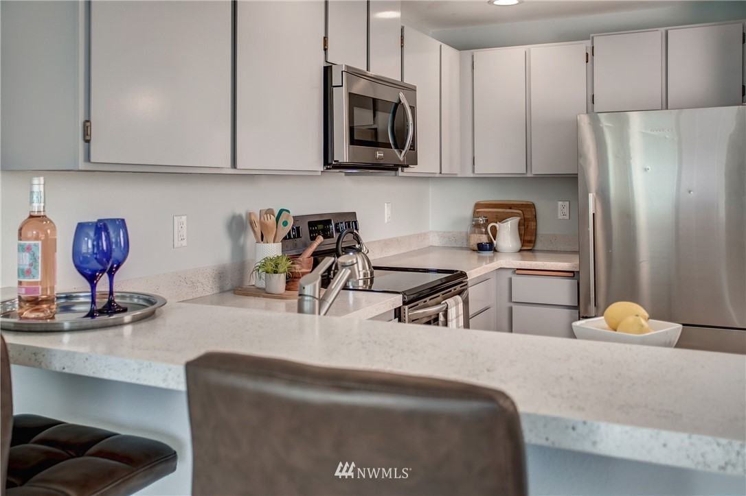 2400 East Howell Street, Unit E Seattle, WA 98122 - Photo 5 of 39 a kitchen with stainless steel appliances granite countertop a refrigerator a stove a sink dishwasher and white cabinets with wooden floor