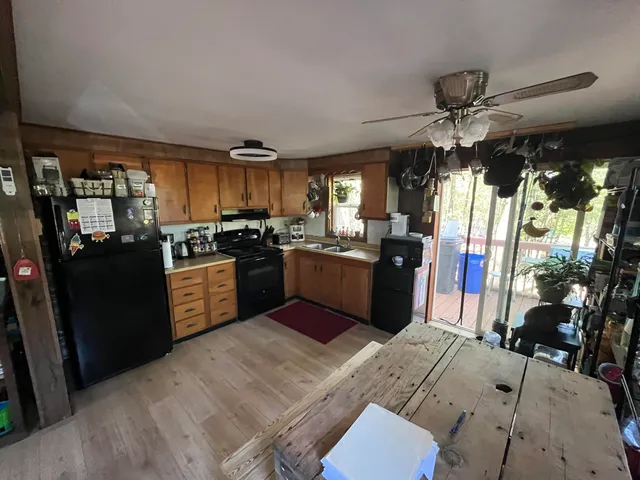 a kitchen with stainless steel appliances kitchen island granite countertop a refrigerator a sink dishwasher a dining table and chairs with wooden floor