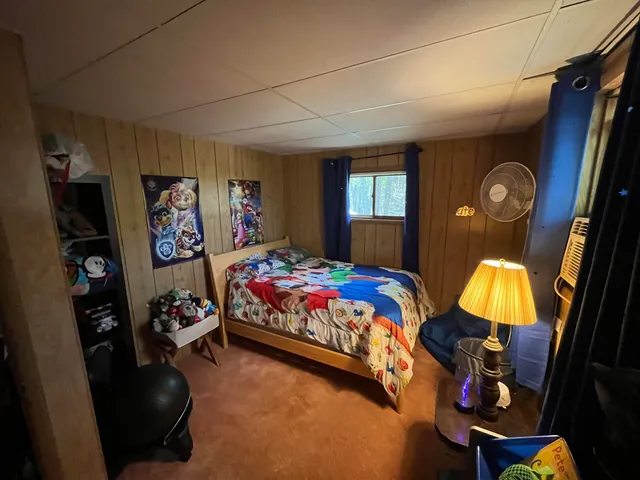 a bedroom with a bed and dresser next to a window