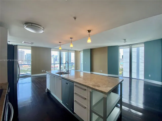 a kitchen with center island wooden floor and stainless steel appliances