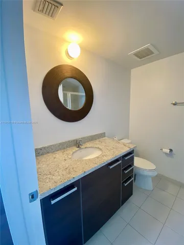 a bathroom with a granite countertop sink and a toilet