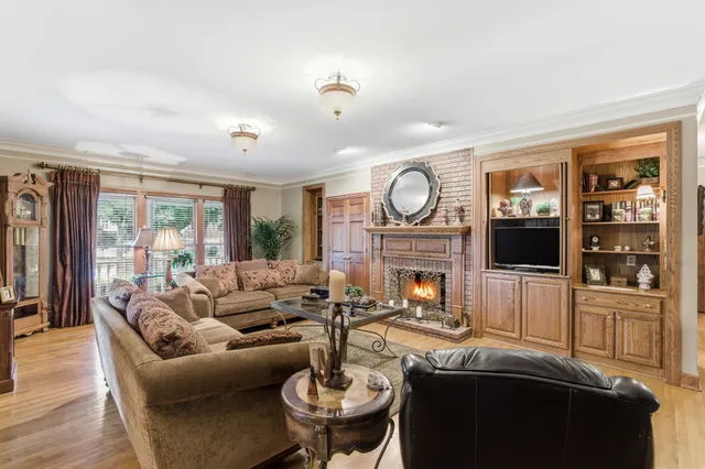 a kitchen with stainless steel appliances kitchen island granite countertop a refrigerator a stove a dining table and chairs with wooden floor