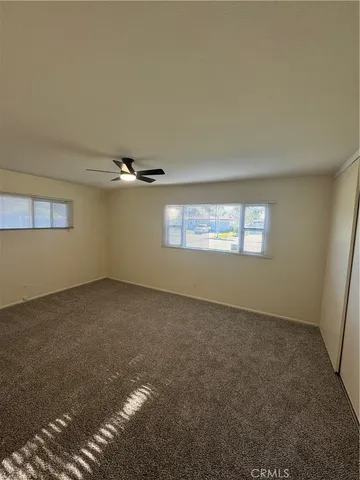 an empty room with windows and ceiling fan view
