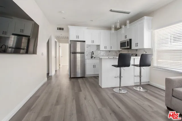 a kitchen with stainless steel appliances wooden floor and refrigerator