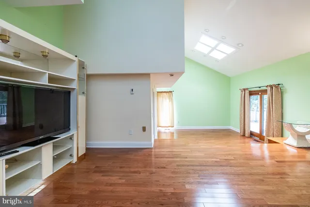 a view of an empty room with window and wooden floor
