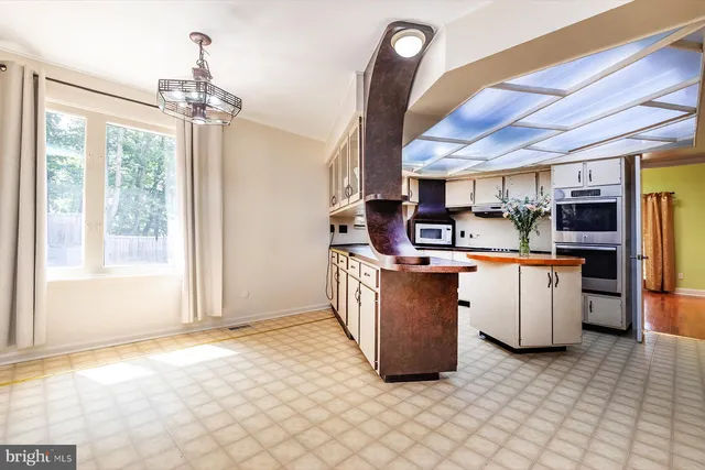 a kitchen with kitchen island a stove a counter top space and cabinets