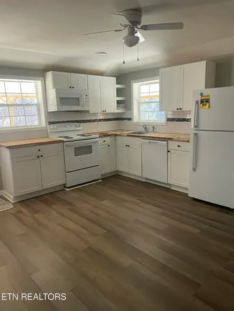 a kitchen with granite countertop white cabinets and white appliances