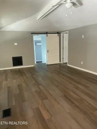 a view of an empty room with wooden floor and windows