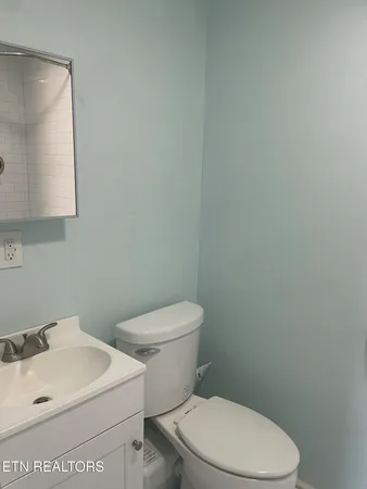 a white toilet sitting next to a white sink and vanity