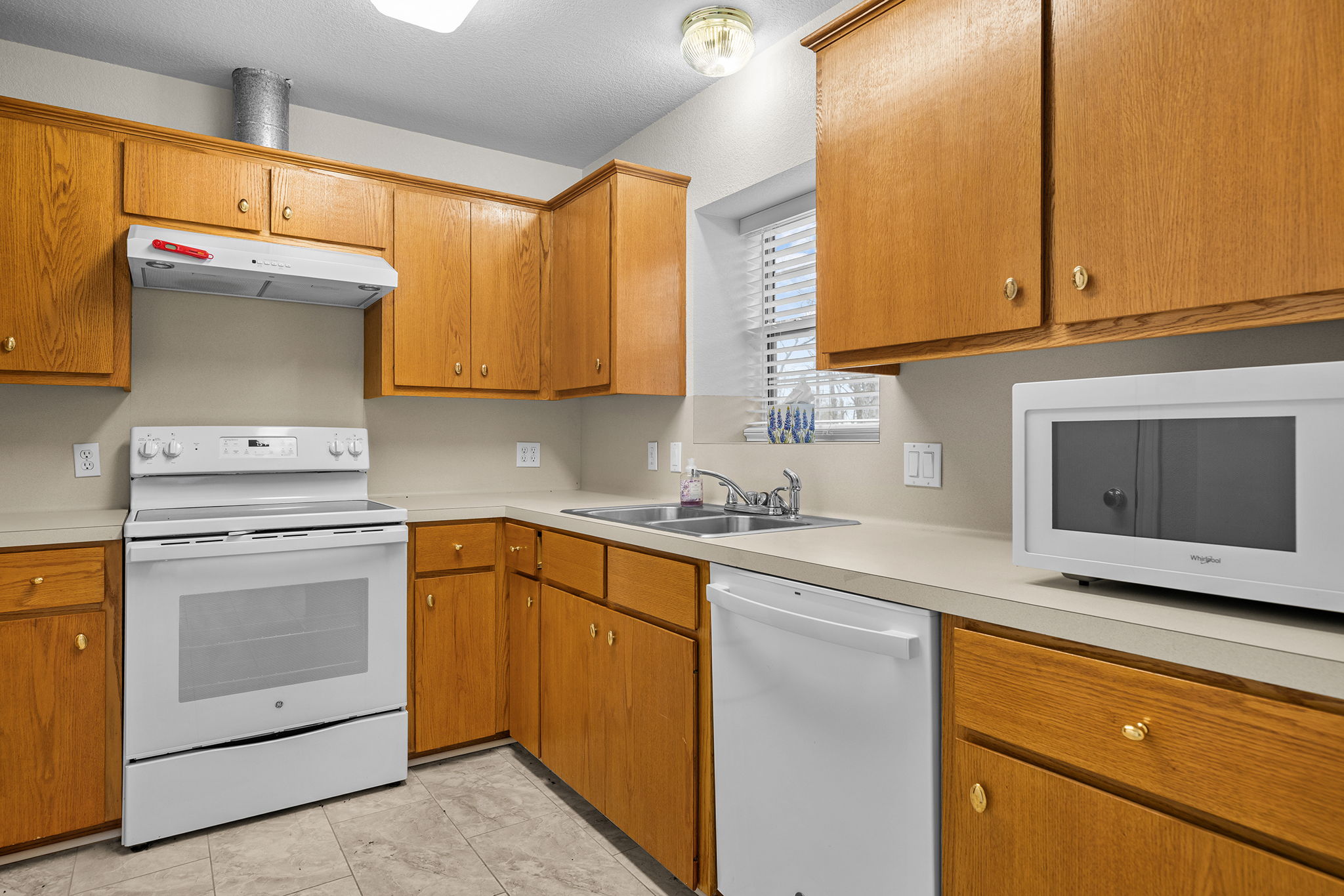 75 County Road 129 Taylor, TX 76574 - Photo 23 of 40 Kitchen featuring white appliances, light countertops, and wood finish cabinetry