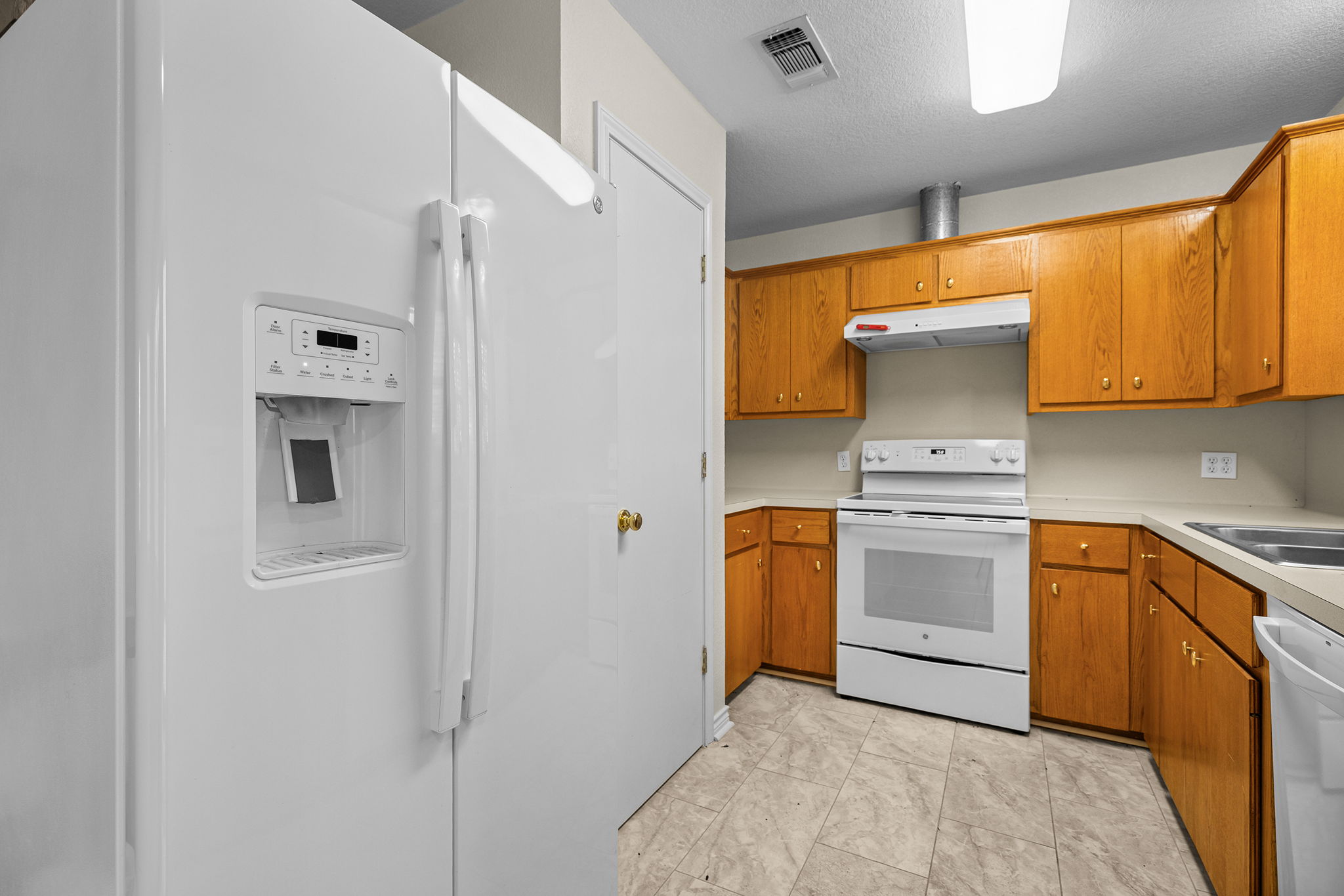 75 County Road 129 Taylor, TX 76574 - Photo 25 of 40 Kitchen with white appliances, wood finish cabinets, light countertops, and a textured ceiling