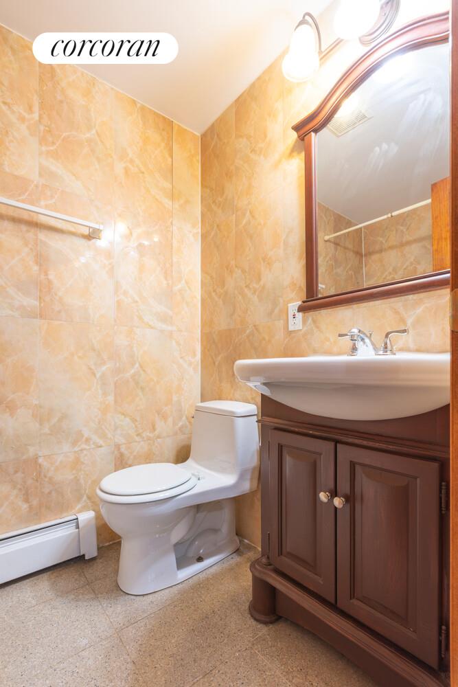 132-36 Pople Avenue, Unit BA Queens, NY 11355 - Photo 8 of 9 a bathroom with a sink mirror vanity and toilet