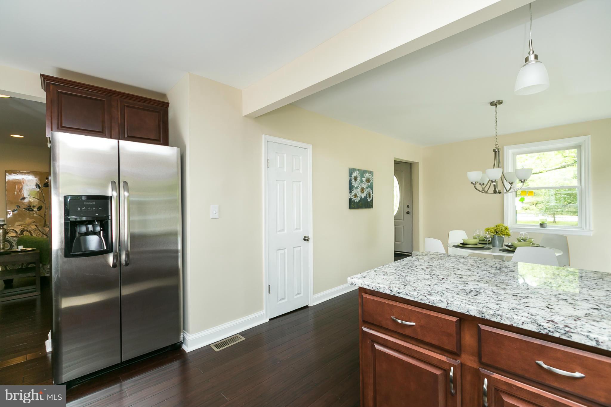 4122 Essex Road Baltimore, MD 21207 - Photo 16 of 30 a kitchen with granite countertop a refrigerator and wooden floor