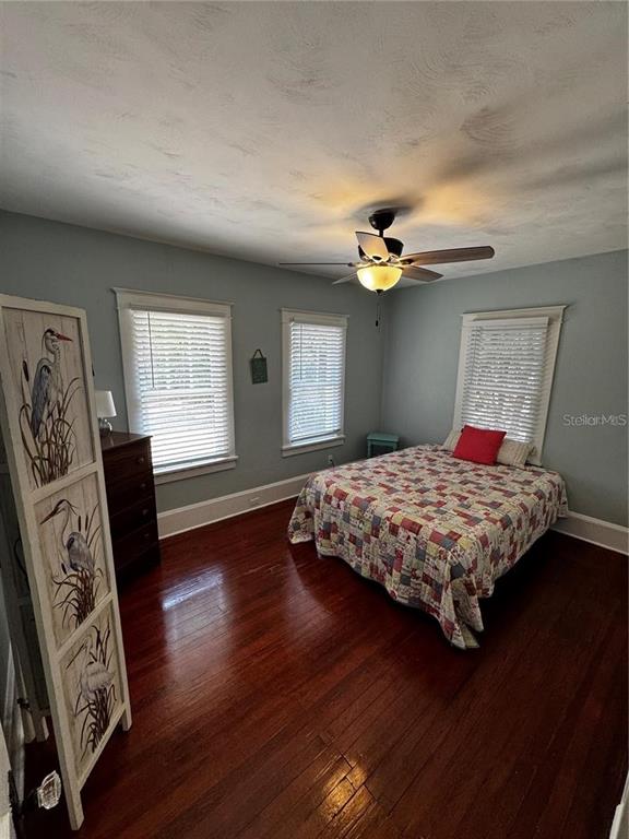 320 North Rhodes Street Mount Dora, FL 32757 - Photo 9 of 33 a bedroom with a large bed chandelier and a window
