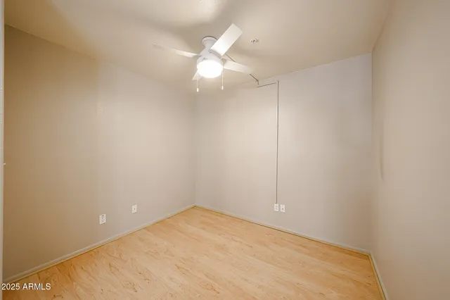 an empty room with a chandelier fan and closet