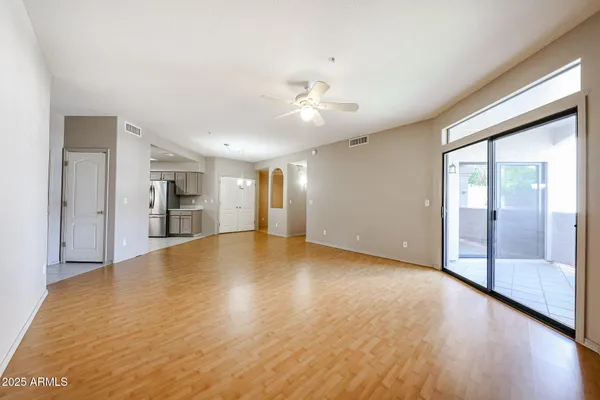 a view of empty room with wooden floor and fan