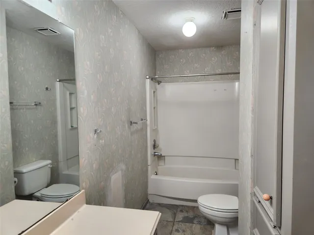 a bathroom with a granite countertop toilet a sink and a shower