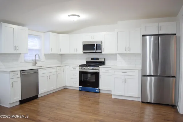 a kitchen with a refrigerator stove and white cabinets