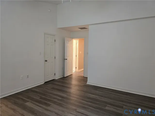 a view of an empty room with wooden floor and closet