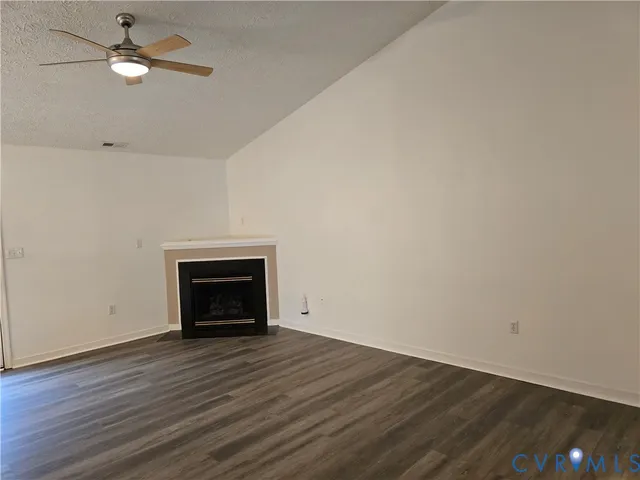 an empty room with wooden floor a fireplace a ceiling fan and wooden floor