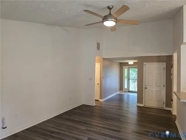 an empty room with wooden floor and a ceiling fan