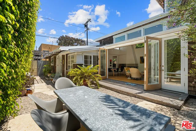 a view of a patio with table and chairs potted plants with floor to ceiling window and potted plants