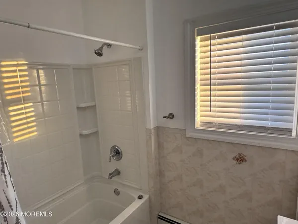 a bathroom with a bathtub a shower and a window